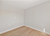 Thumbnail 18 of 25 - A room with wooden flooring and white walls.