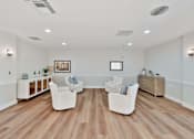 Thumbnail 16 of 25 - A spacious living room with white furniture and wooden flooring.