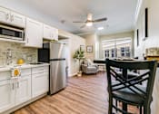 Thumbnail 1 of 19 - A kitchen with white cabinets and a black chair.