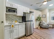Thumbnail 3 of 19 - A kitchen with white cabinets and a stainless steel refrigerator.