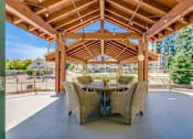 Thumbnail 13 of 19 - A wooden pergola with a table and chairs is set up outside.