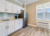 Thumbnail 9 of 19 - A kitchen with white cabinets and a black refrigerator.