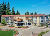 Thumbnail 16 of 19 - A large apartment complex with a parking lot in front.