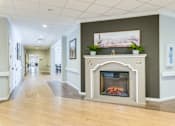 Thumbnail 2 of 10 - A long hallway with a fireplace and a painting on the wall.