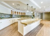 Thumbnail 3 of 10 - A kitchen with a marble countertop and wooden flooring.