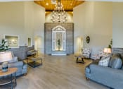 Thumbnail 1 of 10 - A spacious living room with a grey couch, a wooden table, and a chandelier.