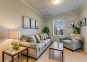Thumbnail 9 of 10 - A living room with a grey couch, a coffee table, and a lamp.