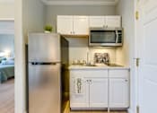 Thumbnail 8 of 10 - A kitchen with a refrigerator, cabinets, and a microwave.