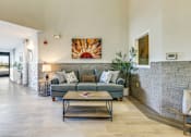 Thumbnail 4 of 10 - A living room with a grey couch and a stone wall.