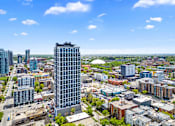 Thumbnail 1 of 5 - A cityscape with a tall building in the foreground and other buildings in the background.
