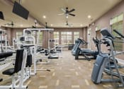 Thumbnail 30 of 40 - a gym with weights and cardio equipment and a ceiling fan