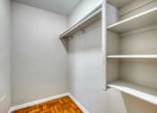 Thumbnail 24 of 24 - an empty closet with white shelves and wood flooring