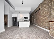 Thumbnail 4 of 8 - A kitchen with a white island and a brick wall.