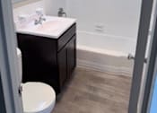 Thumbnail 11 of 40 - A bathroom with a toilet, sink, and mirror.