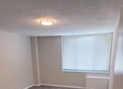 Thumbnail 8 of 40 - A room with a carpeted floor and a window with blinds.