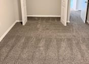 Thumbnail 10 of 40 - A view of the closet in a bedroom with a grey carpet and a white door.