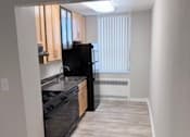 Thumbnail 4 of 40 - A black refrigerator is in a kitchen with white walls.