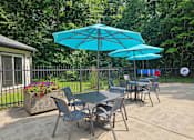 Thumbnail 16 of 31 - A table and chairs set up under a blue umbrella.