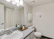 Thumbnail 99 of 111 - A white bathroom with a toilet, sink, and mirror.
