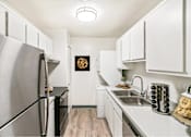 Thumbnail 105 of 111 - A kitchen with a stainless steel refrigerator and white cabinets.