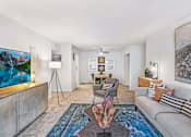 Thumbnail 107 of 111 - A living room with a grey couch, a coffee table, and a painting on the wall.