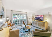 Thumbnail 108 of 111 - A living room with a large screen TV and a view of a fence and trees outside.