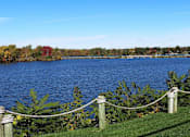 Thumbnail 111 of 111 - A lake surrounded by trees with a rope fence in the foreground.