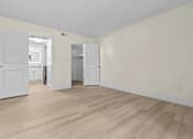 Thumbnail 11 of 111 - A room with white walls and wooden flooring with a door and a cabinet.
