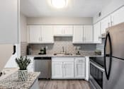 Thumbnail 17 of 111 - A kitchen with a black refrigerator and white cabinets.