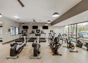 Thumbnail 63 of 111 - A gym with a variety of exercise equipment including treadmills, stationary bikes, and elliptical machines.