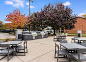 Thumbnail 67 of 111 - A park with tables and chairs surrounded by trees.