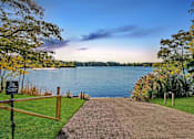 Thumbnail 88 of 111 - A pathway leads to a body of water with a sign on the left.