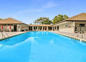 Thumbnail 89 of 111 - A large swimming pool in front of a building with a clear blue sky.