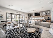 Thumbnail 11 of 26 - A modern living room with a black and white rug, a grey sofa, and a flat screen TV mounted on the wall.