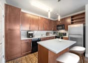 Thumbnail 4 of 26 - A kitchen with brown cabinets and a white island.