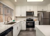 Thumbnail 1 of 28 - Apartments for Rent Oceanside CA - Stone Arbor - White Kitchen with Wood-Style Flooring and Stainless Steel Appliances