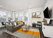 Thumbnail 17 of 26 - A living room with a grey couch, a coffee table, and a television.