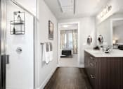 Thumbnail 25 of 26 - A bathroom with a white tile shower, a wooden vanity, and a large mirror.