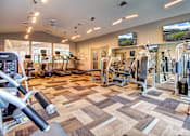 Thumbnail 12 of 24 - a spacious fitness center with cardio equipment and flat screen tvs