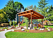 Thumbnail 20 of 24 - an outdoor kitchen with a wooden awning and stone pillars