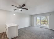 Thumbnail 13 of 19 - a bedroom with a large window and a ceiling fan
