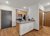 Thumbnail 21 of 27 - A kitchen with wooden cabinets and a black door.
