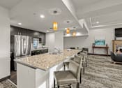 Thumbnail 18 of 27 - A kitchen with a granite countertop and a dining area with chairs.