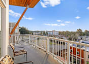 Thumbnail 26 of 27 - A balcony with a chair and a table overlooking a street.