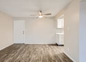 Thumbnail 21 of 28 - an empty living room with a ceiling fan and a kitchen