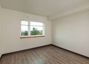 Thumbnail 22 of 36 - Empty room with a window and wooden floor.