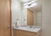 Thumbnail 25 of 36 - A bathroom with a sink, mirror, and light.