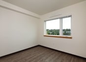 Thumbnail 27 of 36 - Empty room with a window overlooking a tree-filled landscape.