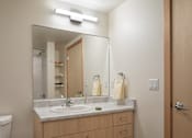 Thumbnail 28 of 36 - A bathroom with a sink, mirror, and toilet.