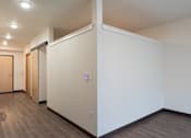 Thumbnail 31 of 36 - A room with a white wall and a brown floor.